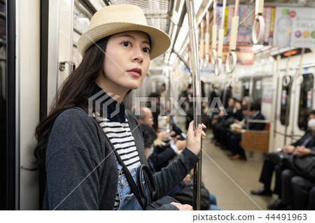 a female traveler wearing a straw hat taking MRT a female traveler wearing a straw hat taking MRT 44491963