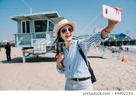 traveler taking selfie by her pink smartphone 44492250