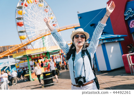 joyful female traveler raising arms to the sky 44492261