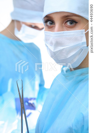 Surgeon doctor in mask performing operation. Focus on female intern girl. Medicine, emergency help 44493690