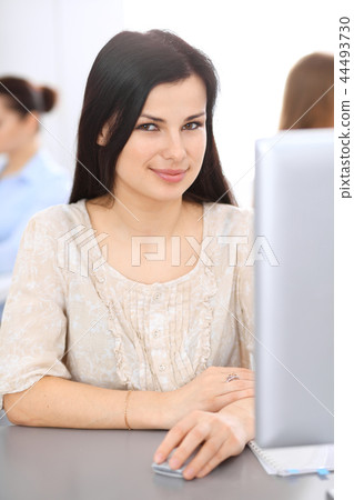 Young brunette businesswoman working at office with computer. Customer service and business concept Young brunette businesswoman working at office with computer. Customer service and business concept 44493730