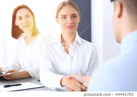 Business handshake by blonde woman and her partner at meeting. Concept of success and agreement Business handshake by blonde woman and her partner at meeting. Concept of success and agreement 44493765