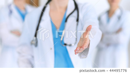 Group of medicine doctors offering helping hand  for shaking hand or saving life closeup. Partnershi 44495776