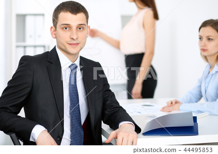 Portrait of a young business man against a group of business people at a meeting Portrait of a young business man against a group of business people at a meeting 44495853