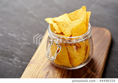 jar full of delicious cheese nachos on an old black wooden table jar full of delicious cheese nachos on an old black wooden table 44496359