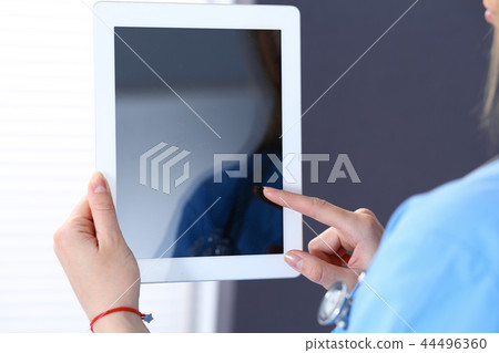 Woman doctor using tablet computer while standing straight in hospital office, closeup. Healthcare 44496360