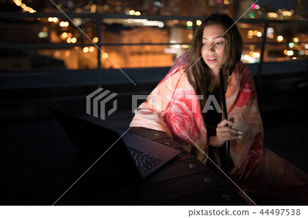Girl sits wrapped in a blanket and smokes a hookah. 44497538