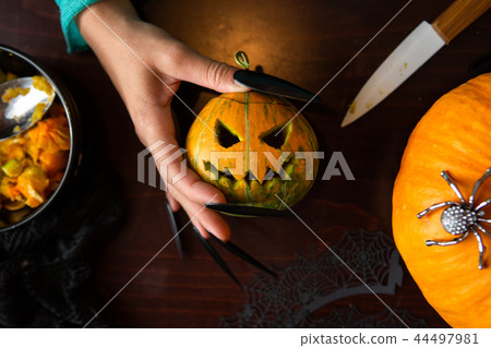 Photo of man's hands with pumpkin jack, knife sitting at wooden table Photo of man's hands with pumpkin jack, knife sitting at wooden table 44497981