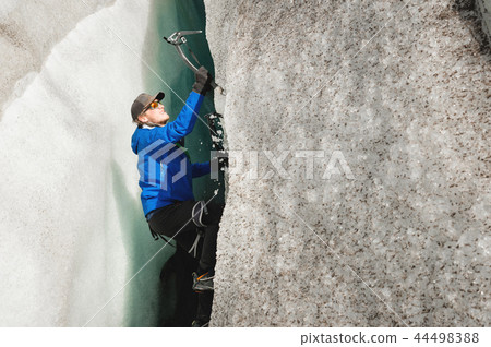 A free climber without insurance with two ice axes rises from a crack in the glacier. Free climbing 44498388
