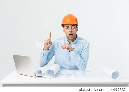 Confident smiling architect in formal wear thinking and working with blueprint papers and drawings Confident smiling architect in formal wear thinking and working with blueprint papers and drawings 44499882