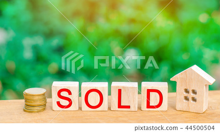 wooden house and coins with the inscription "sold" 44500504