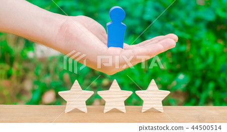 The hand holds a human figure and three stars. 44500514