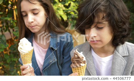 cute teenagers, boy and girl eating ice cream in the park and talking cute teenagers, boy and girl eating ice cream in the park and talking 44506777