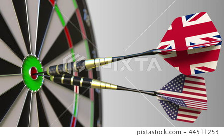 Flags of the United Kingdom and the USA on darts hitting bullseye of the target. International 44511253