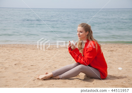 woman drinking hot coffee or tea on the sandy beach 44511957