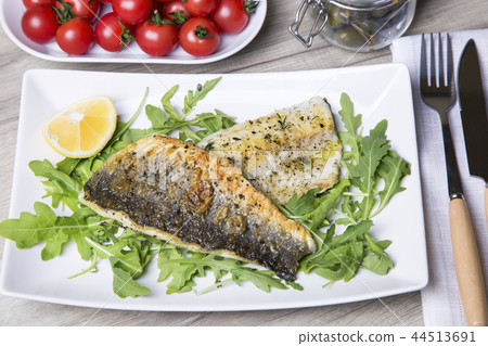 Grilled seabass fillet with arugula, lemon 44513691