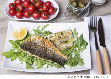 Grilled seabass fillet with arugula, lemon 44513693