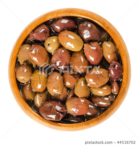Pitted Taggiasca olives in wooden bowl over white Pitted Taggiasca olives in wooden bowl over white 44516702