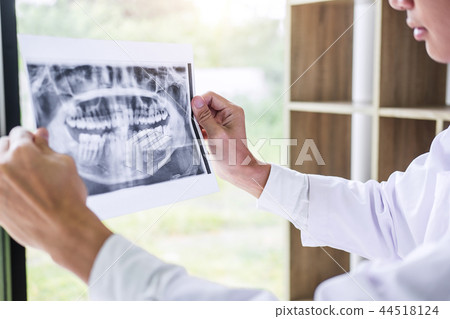 Image of male doctor or dentist holding and looking at dental x- 44518124