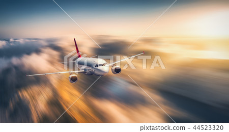 White airplane is flying in low clouds at sunset 44523320