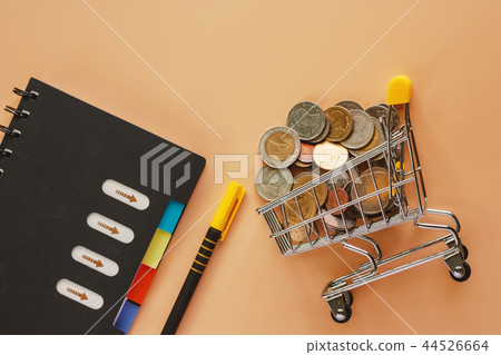 Coins in mini shopping cart with office supplies 44526664