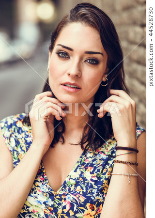 Young woman with blue eyes standing next to brick wall 44528730