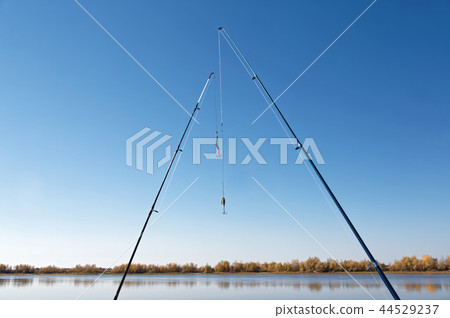 Two spinning rods on the background of the bank of the autumn river 44529237