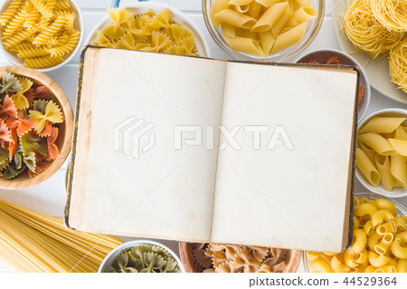 Various types of italian pasta and blank cookbook. 44529364