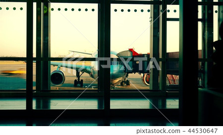 Airport shot involving airfield traffic and boarding airplane with attached jet bridge 44530647