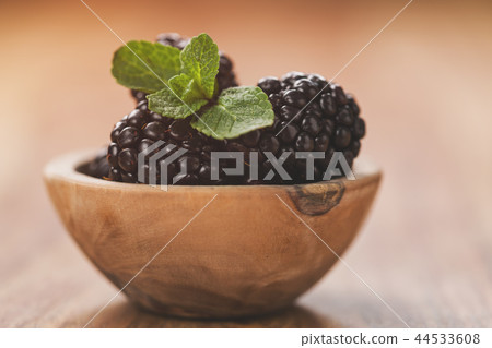 fresh blackberries in wood bowl on wooden table with mint leaves 44533608