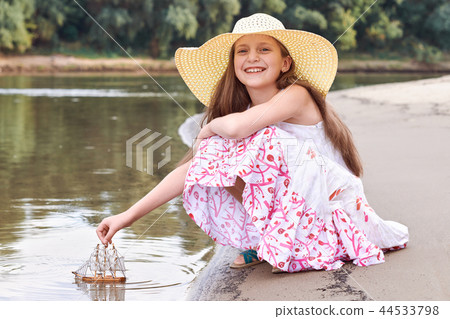 girl child playing with toy sailing ship by river girl child playing with toy sailing ship by river 44533798