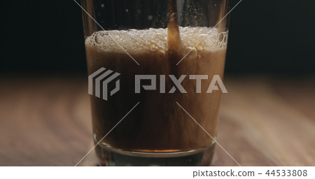 closeup pan of stout beer pour into a glass on wooden table 44533808