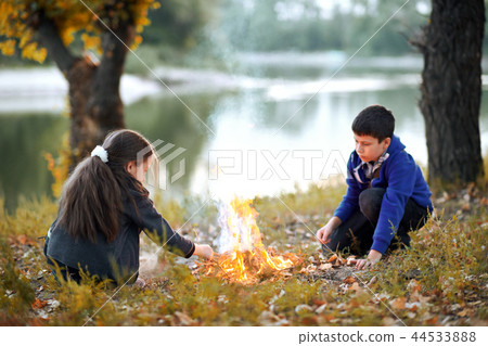 boy and girl sitting on the river Bank make a fire boy and girl sitting on the river Bank make a fire 44533888