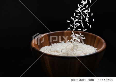 Pouring jasmine rice into a wooden bowl 44538690