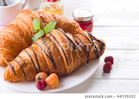 Fresh tasty croissants with berries on white wooden background 44539101