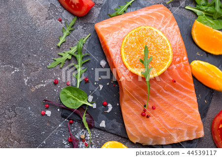 Salmon raw close up. Salmon red fish steak with herbs and orange on a stone background Salmon raw close up. Salmon red fish steak with herbs and orange on a stone background 44539117