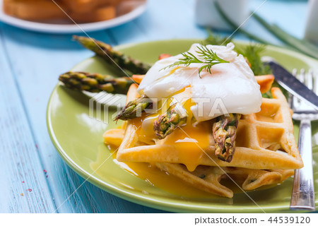 Grilled waffle with Green boiled Asparagus with Poached Egg, with salt and spices on ceramic plate 44539120