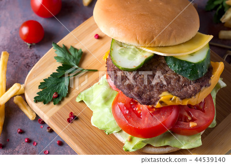 Tasty grilled home made burger cooking with beef, tomato, cheese, cucumber and lettuce. Top view 44539140
