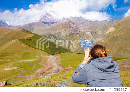 girl looking in binoscope directed towards the snowy mountain tops of Kazbeg from the view point girl looking in binoscope directed towards the snowy mountain tops of Kazbeg from the view point 44539217