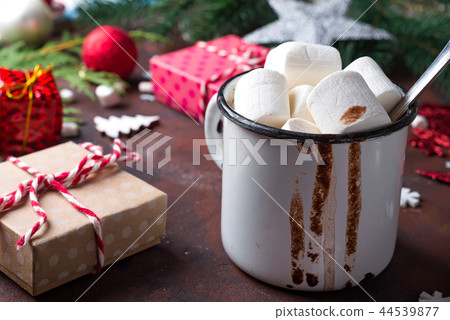 Enamel cup of hot cocoa with mini marshmallows with pine boughs against a white background with Enamel cup of hot cocoa with mini marshmallows with pine boughs against a white background with 44539877