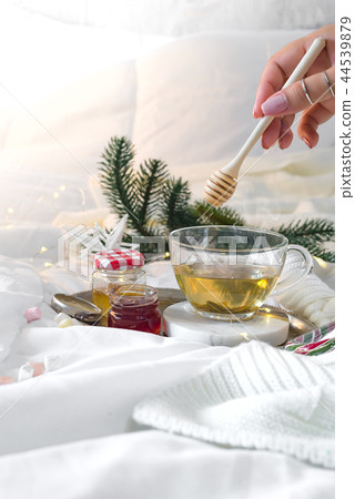 tray with honey and a cup of hot tea in the bed and woman hands , lazy morning, warm winter mood 44539879