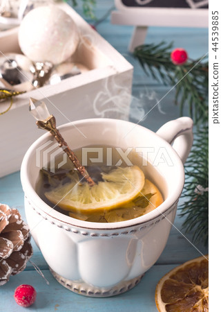 Winter time. Cup of hot tea with lemon, christmas toys and woolen scarf. Close up Winter time. Cup of hot tea with lemon, christmas toys and woolen scarf. Close up 44539885