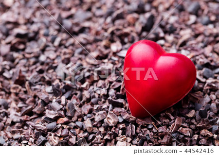 Heart shaped chocolate candy on crushed cocoa nibs. Close up. Copy space. 44542416