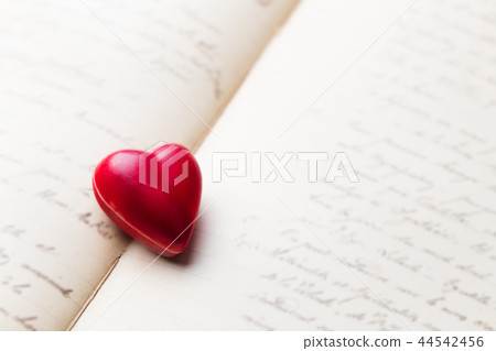 Chocolate heart shaped candy on vintage book with hand writing. Copy space. 44542456
