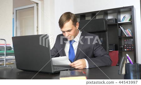 A man is studying a paper document. Sitting in the office A man is studying a paper document. Sitting in the office 44543997