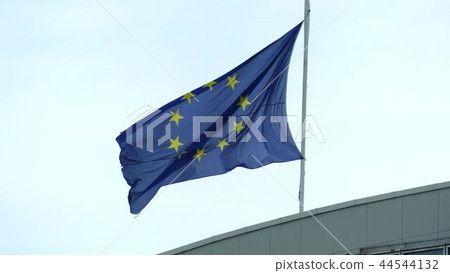 Waving worn flag of the European Union on the roof of a building 44544132