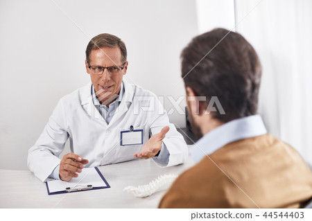 Doctor is talking with young man in cabinet Doctor is talking with young man in cabinet 44544403