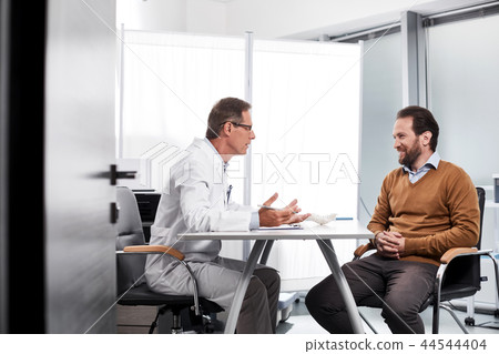 Adult doctor talking with patient in bright office 44544404