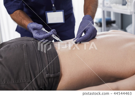 Doctor is making an injection in back of man Doctor is making an injection in back of man 44544463
