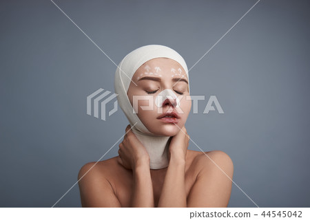 Young lady wearing bandages and closing her eyes 44545042